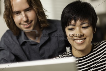 Pretty Smiling Multiethnic Woman and Caucasian Man Using A Laptop Computer Together.