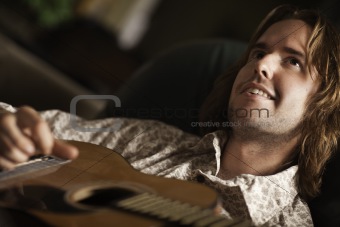 Young Musician Plays His Accustic Guitar under Dramatic Lighting.
