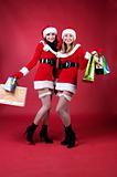Two women in dressed as Santa, with shopping bags . 