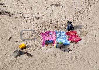 Three beach towels abandoned over sand