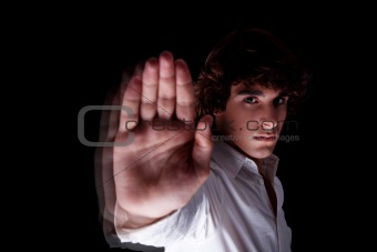 cute boy with his hand raised in signal to stop, isolated on black background, Studio shot