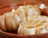 Fresh garlic roasting in olive oil in a clay pot - shallow DOF
