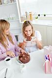 Delighted female friends eating a chocolate cake in the kitchen