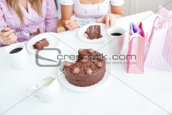 Close-up of caucasian female friends eating a chocolate cake in 
