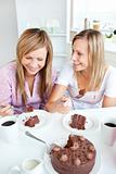 Merry female friends eating a chocolate cake in the kitchen