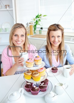 Portrait of two female friends eating pastries and drinking coff