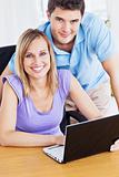 Smiling couple using computer on the desk 