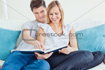 Beautiful loving couple reading a book on the sofa