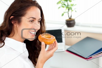 Hispanic businesswoman eating a doughnut in her office