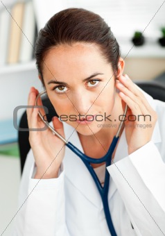 Confident female doctor using a stethoscope in her office