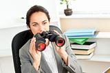 Serious hispanic businesswoman looking through binoculars 