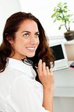 Attractive businesswoman holding glasses and sitting at her desk