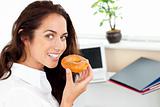 Happy hispanic businesswoman eating a doughnut