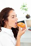 Charming hispanic businesswoman eating a doughnut
