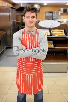 Confident cook smiling at the camera in front of his bakery