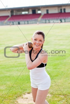 Delighted female athlete holding weight in a stadium
