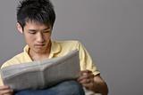 Asian young man reading newspaper