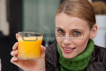 woman holding a glass of orange juice and looking at camera