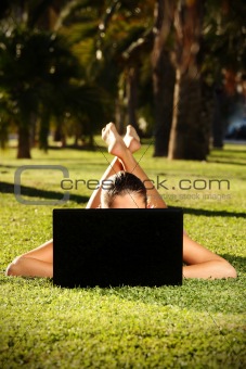 Barefoot woman on a grass with a laptop