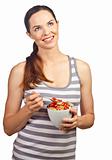 Beautiful young woman eating a bowl of cereal with strawberries
