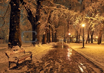 bench and shining lantern through snowing