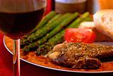 Meal of porkchops, asparagus, tomatoes and bread