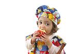 Little girl eating an apple dressed as a chef