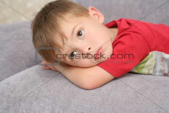 The sad boy lays on a sofa