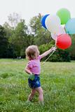 girl with balloon runs on lawn