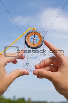 hand with compass on background sky