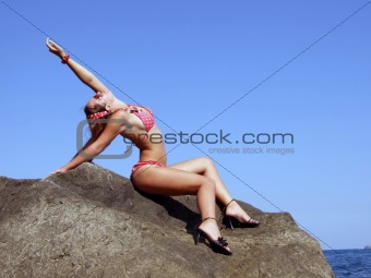 The sexual girl sits on a rock on a background of the sky2