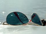 The sunglasses laying on a white surface on a background of wate