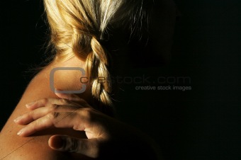 Abstract dramatically lit image of woman's shoulder, hand and blond hair.