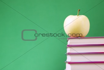 Yellow apple placed on books
