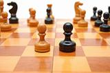 Vintage chessmen on chess board. White pawn against black one.