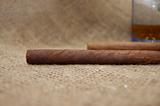 Two cuban cigars and glass with wiskey on sackcloth