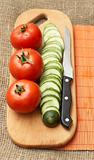 Tomatoes, cucumber and knife on kitchen board