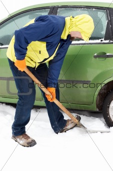 Man digging car wheels from the snow
