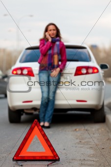 Woman calls to a service standing by a white car