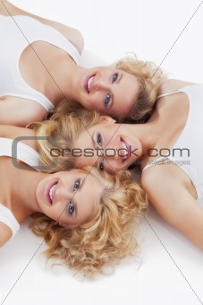 three young women lying on the floor, looking up- isolated on white