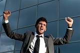 Young successful businessman celebrating a goal on a modern building background