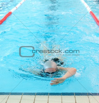 young woman swims in indoor pool. freestyle mode.