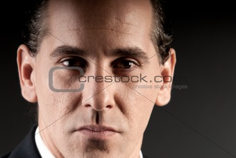 Adult businessman closeup portrait on dark background.