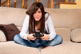 Young female concentrating playing videogames on sofa at home