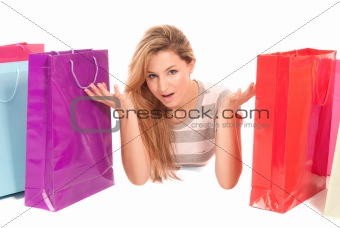 Young woman with shopping bags lying on floor on white background