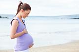 Pregnant woman touching her belly on the beach