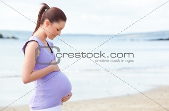 Pregnant woman touching her belly on the beach