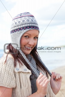 Frozen woman with scarf and colorful hat standing on the beach