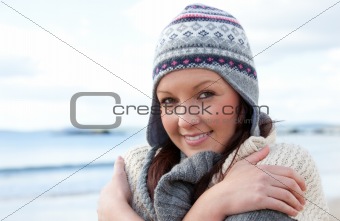 Frozen woman with scarf and colorful hat standing on the beach