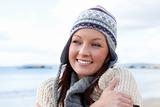 Joyful woman wearing hat and scarf on the beach